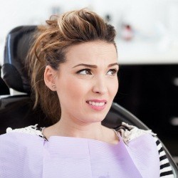 Woman in need of sedation dentistry covering her smile