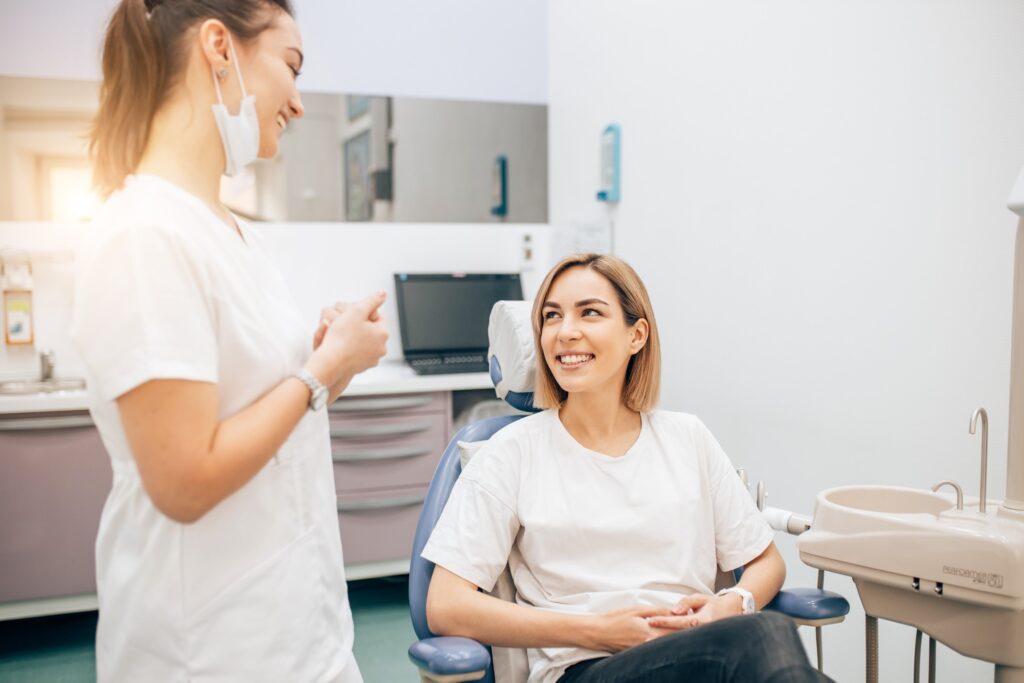 Smiling dental assistant and patient talking in office